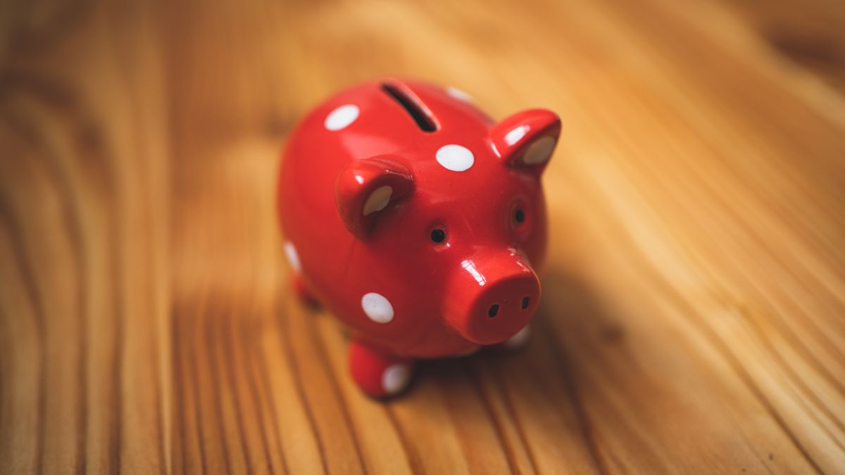 木目の机に置かれた貯金箱(お金の全体像のイメージ)